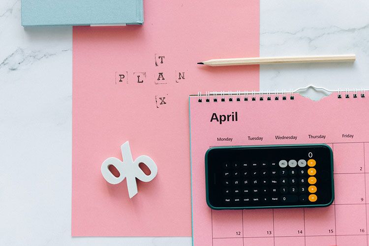 iphone on top of pink paper with calendar and tax plan